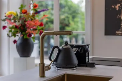 a kitchen sink with a tea kettle and a vase of flowers at De Lindekamer in Loenen aan de Vecht