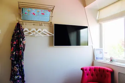 a living room with a tv and a red chair at Bubbles & Bed in Bilthoven