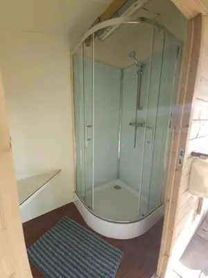 a glass shower in a bathroom with a rug at Trekkershut - De Hollandse Boerderij in Ons Belang