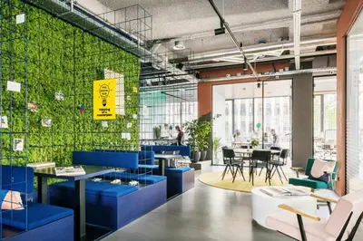 a room with blue chairs and tables and a green wall at The Social Hub Amsterdam West Extended Stay in Amsterdam