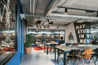 a dining room with tables and chairs and a large window at The Social Hub Amsterdam West Extended Stay in Amsterdam