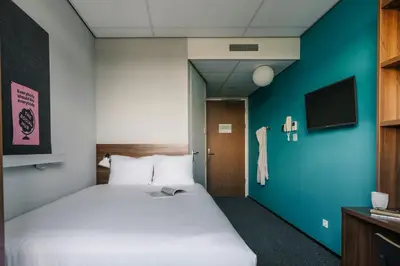 a bedroom with a white bed and a blue wall at The Social Hub Amsterdam West Extended Stay in Amsterdam