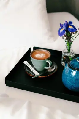a cup of coffee and a vase of flowers on a tray at The Social Hub Amsterdam West Extended Stay in Amsterdam