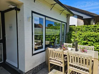 a patio with two chairs and a table with flowers at Bed and Beach in Schoorl in Schoorl