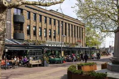 a large building with people sitting outside of it at Manzo's Suites in Zaandam