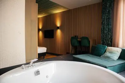 a bathroom with a tub and a couch and a mirror at Manzo's Suites in Zaandam