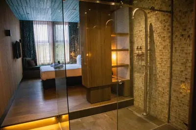 a bathroom with a shower and a bed in a room at Manzo's Suites in Zaandam