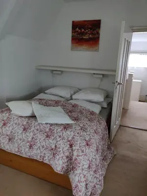 a bedroom with a bed with a floral bedspread and pillows at Zit slaapkamer op de 2e etage in een rietgedekte villa met gedeelde douche en keuken in Wassenaar