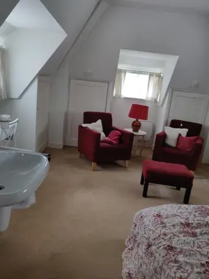 a bathroom with a sink and two chairs and a couch at Zit slaapkamer op de 2e etage in een rietgedekte villa met gedeelde douche en keuken in Wassenaar