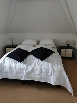 a white bed with a black and white comforter at Zit slaapkamer op de 2e etage in een rietgedekte villa met gedeelde douche en keuken in Wassenaar