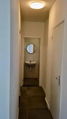 a hallway with a bathroom with a sink and a mirror at Y Hostel in Amsterdam
