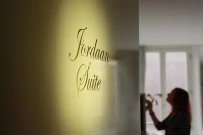 a woman standing in a room with a sign on a wall at Jordaan Suite bed and bubbles in Amsterdam