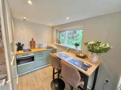 a kitchen with blue cabinets and a table with flowers on it at Bed and Breakfast Verlaat in Oude-Niedorp