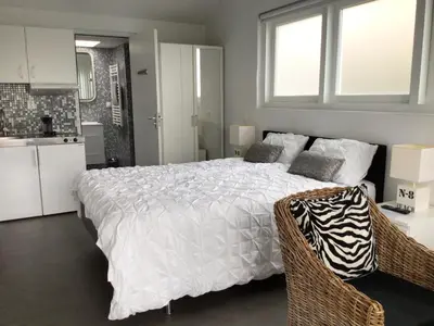 a bedroom with a white bed and a kitchen at Studio Sunrise in Zandvoort