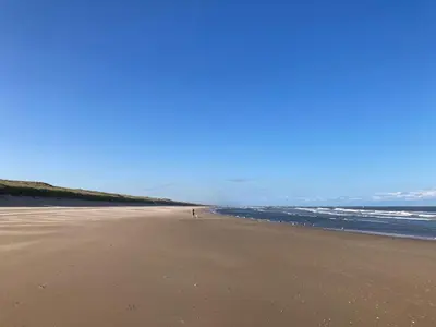 a beach with a person standing on the sand at Studio Sunrise in Zandvoort