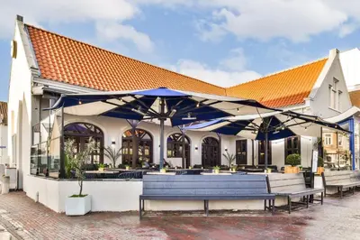 a building with blue umbrellas and benches in front of it at Loft Studio's in Zandvoort