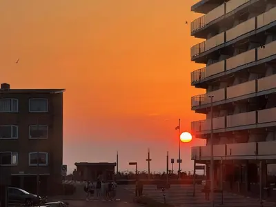 a sunset in a city with a building and people at Short Stay Zandvoort at 68 in Zandvoort