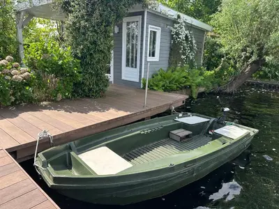 a green boat sitting on the water next to a dock at Amsterdam lake area, super wifi island incl boat in Vinkeveen
