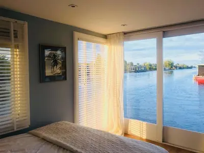 a bedroom with a large window with a view of the water at Amsterdam lake area, super wifi island incl boat in Vinkeveen