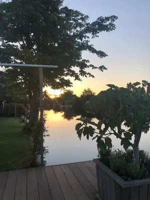 a sunset over a lake with a wooden deck at Amsterdam lake area, super wifi island incl boat in Vinkeveen