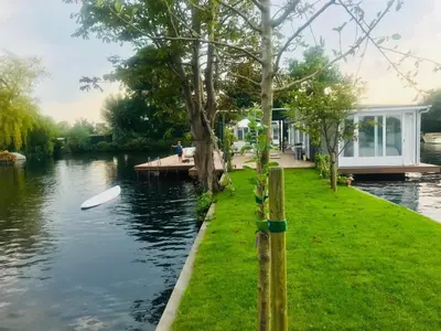 a white boat on the water next to a house at Amsterdam lake area, super wifi island incl boat in Vinkeveen
