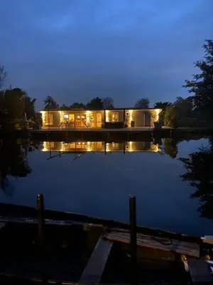 a house sitting on a lake at night at Amsterdam lake area, super wifi island incl boat in Vinkeveen