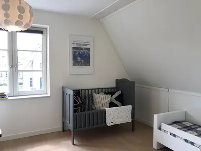 a baby room with a crib and a window at House with garden in Amsterdam in Weesp