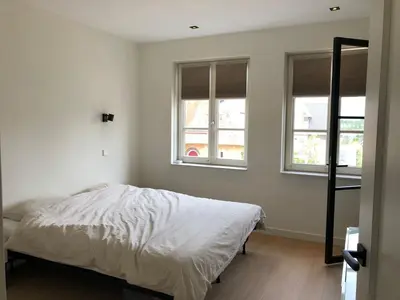 a bedroom with a bed and two windows at House with garden in Amsterdam in Weesp