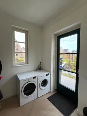 a laundry room with a washing machine and a window at House with garden in Amsterdam in Weesp