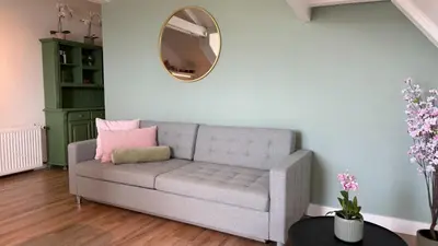 a living room with a couch and a mirror at De Toerist Thuis Bij De Sluis in Spaarndam