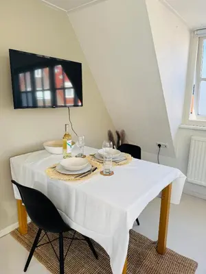 a dining room table with a white table cloth on it at tiny beach house noordwijk in Noordwijk aan Zee