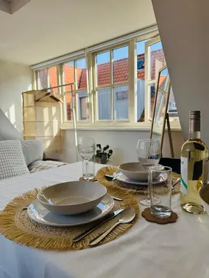 a table with two plates and wine glasses on it at tiny beach house noordwijk in Noordwijk aan Zee