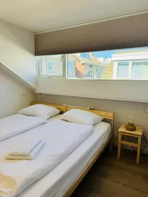 two beds in a room with a window at familie huisje de kleine schelp in Noordwijk aan Zee