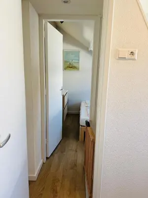 a hallway with a hallway leading to a room with a bed at familie huisje de kleine schelp in Noordwijk aan Zee