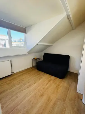 a room with a black couch in a attic at familie huisje de kleine schelp in Noordwijk aan Zee