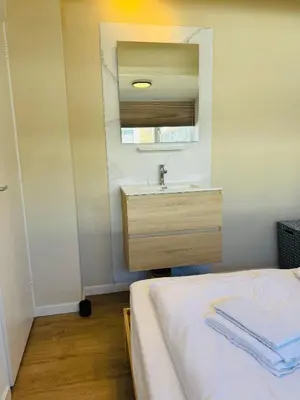 a bathroom with a sink and a bed with a mirror at familie huisje de kleine schelp in Noordwijk aan Zee