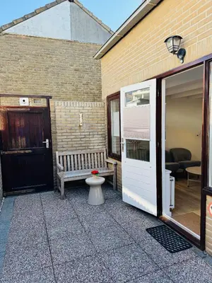 a patio with a bench and a toilet in front of a building at familie huisje de kleine schelp in Noordwijk aan Zee