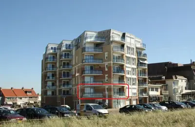 a tall building with cars parked in a parking lot at Atlantis 14a in Egmond aan Zee