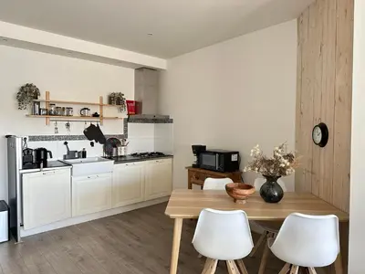 a kitchen with a wooden table and white cabinets at Zin aan Zee in Egmond aan Zee