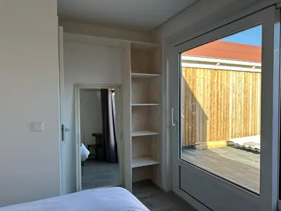 a bedroom with a glass door leading to a balcony at Zin aan Zee in Egmond aan Zee