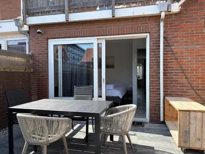 a patio with a table and chairs and a bedroom at Zin aan Zee in Egmond aan Zee