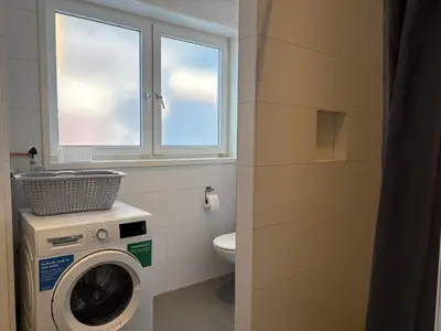 a bathroom with a washing machine and a toilet at Zin aan Zee in Egmond aan Zee