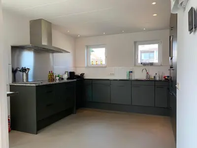 a kitchen with black cabinets and a sink at Heerlijke villa met zwembad en sauna bij het strand in Bergen aan Zee
