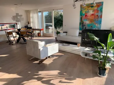 a living room with a couch and a tv at Heerlijke villa met zwembad en sauna bij het strand in Bergen aan Zee