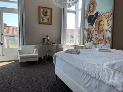 a bedroom with a white bed and a large window at Heerlijke villa met zwembad en sauna bij het strand in Bergen aan Zee