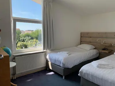 a hotel room with two beds and a window at Heerlijke villa met zwembad en sauna bij het strand in Bergen aan Zee