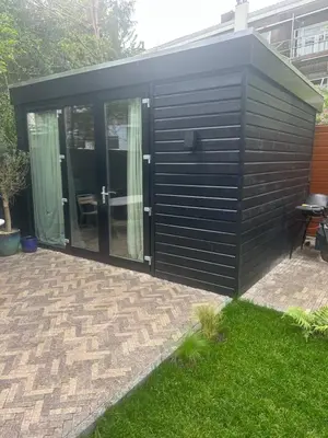 a black shed with glass doors in a yard at Spacious and lovely home in Amsterdam