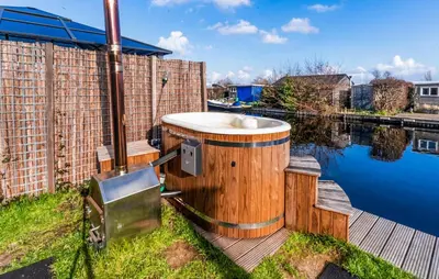 a wooden tub sitting on a deck next to a body of water at Beautiful Home In Vinkeveen With Sauna in Vinkeveen