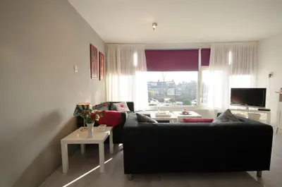 a living room with a black couch and a window at Casa Luma in Zandvoort