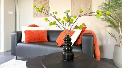 a vase with flowers on a table in front of a couch at 't Boschhuys by Droomvilla in Bergen